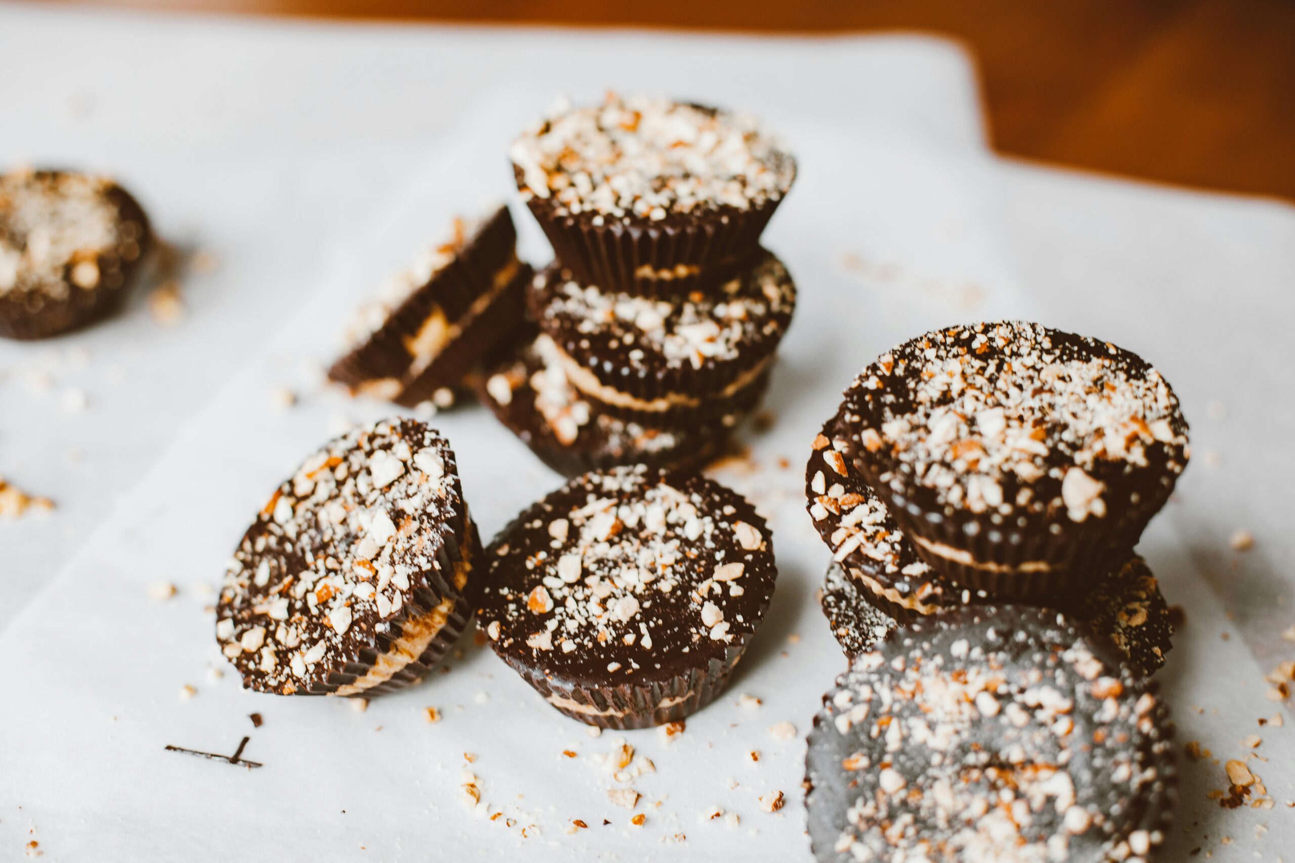 Close-up of chocolate muffins topped with crunchy nuts on a white surface, perfect dessert treat.